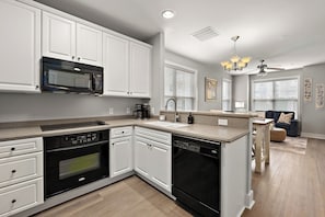 A modern kitchen with white cabinetry, a built-in microwave, a dishwasher, and a coffee maker. - Midtown 3BR Townhouse, Walk to Beach, Sleeps 10, Linens Included (Ocean City)