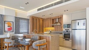Una cocina moderna con una isla central, electrodomésticos integrados y un comedor con sillas estampadas.