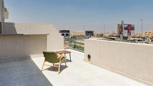 Una terraza en la azotea con una silla verde, una mesita y vistas despejadas del paisaje urbano.