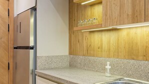 Eine moderne Küche mit Edelstahlkühlschrank, Granitarbeitsplatte, Holzausbau und einer eingebauten Ablage mit Gläsern.
