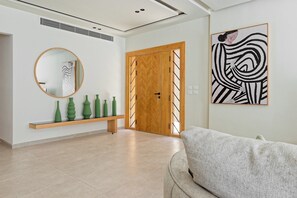 A modern interior with a wooden door, a round mirror, and a green vase shelf. - VESTA  - Luxury Duplex - 3BR - Zayed City I (Sheikh Zayed City)