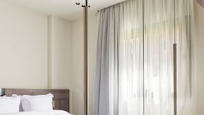 Una habitación de hotel moderna con una cama grande, cabecero de madera y un espejo grande que refleja la habitación.