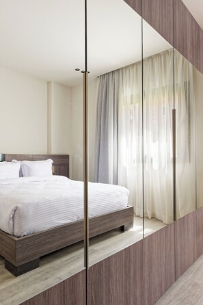A modern hotel room with a large bed, wooden headboard, and a large mirror reflecting the room. - VESTA  - Luxury Duplex - 3BR - Zayed City I (Sheikh Zayed City)