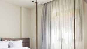Ein modernes Hotelzimmer mit einem großen Bett, einem Holzkopfende und einem großen Spiegel, der den Raum reflektiert.