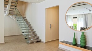 Ein modernes Interieur mit einer Glaswendeltreppe, einer Holztür und einem runden Spiegel an der Wand.