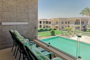 Ein Balkon mit Stühlen und Blick auf einen Pool und Gebäude.