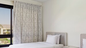 Habitación de hotel con dos camas, una ventana con vistas y una lámpara en el techo.