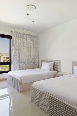 Ein Hotelzimmer mit zwei Betten, einem Fenster mit Aussicht und einer Deckenleuchte.