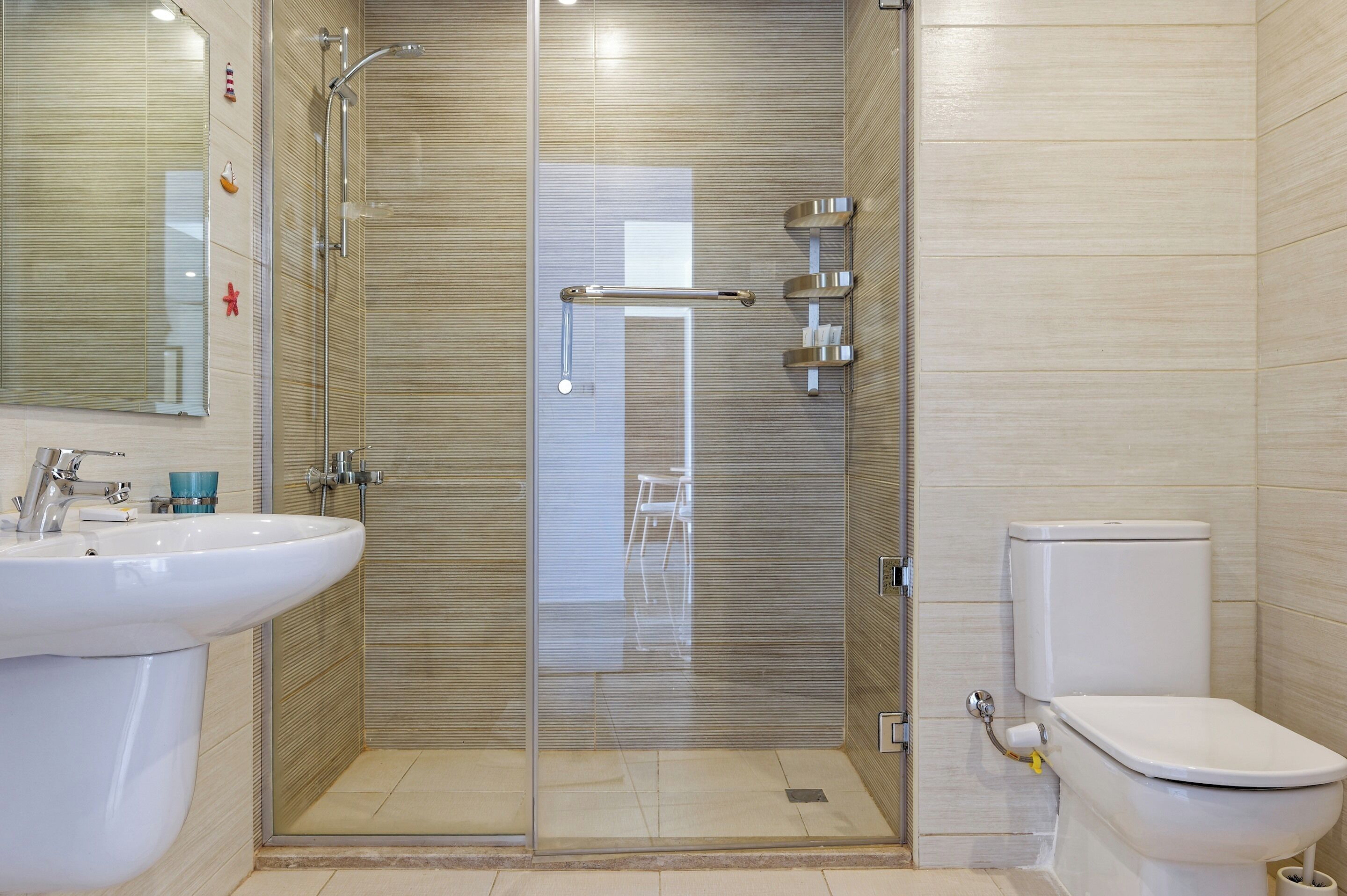 A bathroom with a glass-enclosed shower, a white sink, and a toilet.