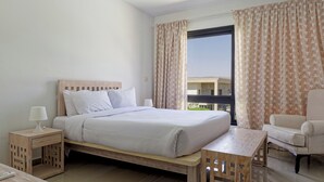Habitación de hotel con cama, mesitas de noche, una silla y vistas al exterior.