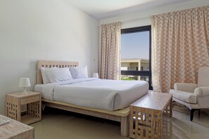 Ein Hotelzimmer mit Bett, Nachttischen, einem Sessel und Blick ins Freie.
