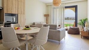 Ein modernes Wohnzimmer mit Essbereich, einem Fernseher und Blick auf den Strand.