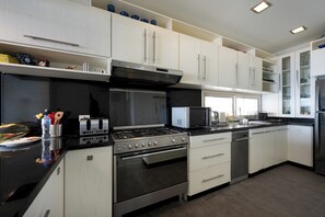 A modern kitchen with stainless steel appliances, white cabinetry, and a black countertop. - VESTA - Luxury Apt - 3BR - Marina Soma Bay (Hurghada)
