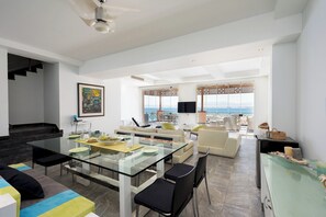 A spacious living area with a glass dining table, comfortable seating, a staircase, and a view of the ocean. - VESTA - Luxury Apt - 3BR - Marina Soma Bay (Hurghada)