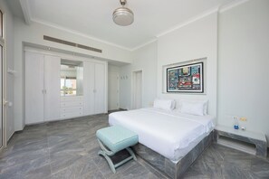 A bedroom with a large bed, a bench, a wardrobe, and a ceiling fan. - VESTA - Luxury Apt - 3BR - Marina Soma Bay (Hurghada)