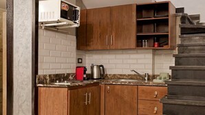 Een keuken met houten kastjes, een magnetron, een koffiezetapparaat en een trap.