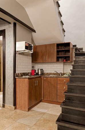 Eine Küche mit Holzausstattung, einer Mikrowelle, einer Kaffeemaschine und einer Treppe.