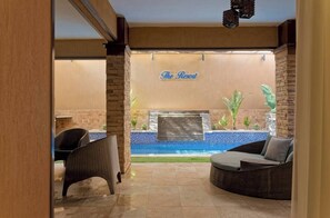 Ein Hotelinterior mit Korbmöbeln, einem Pool und einem Schild mit der Aufschrift 'The Resort'.