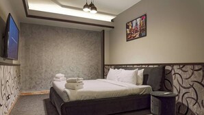 Een hotelkamer met een bed, een televisie, een schilderij en een nachtkastje.
