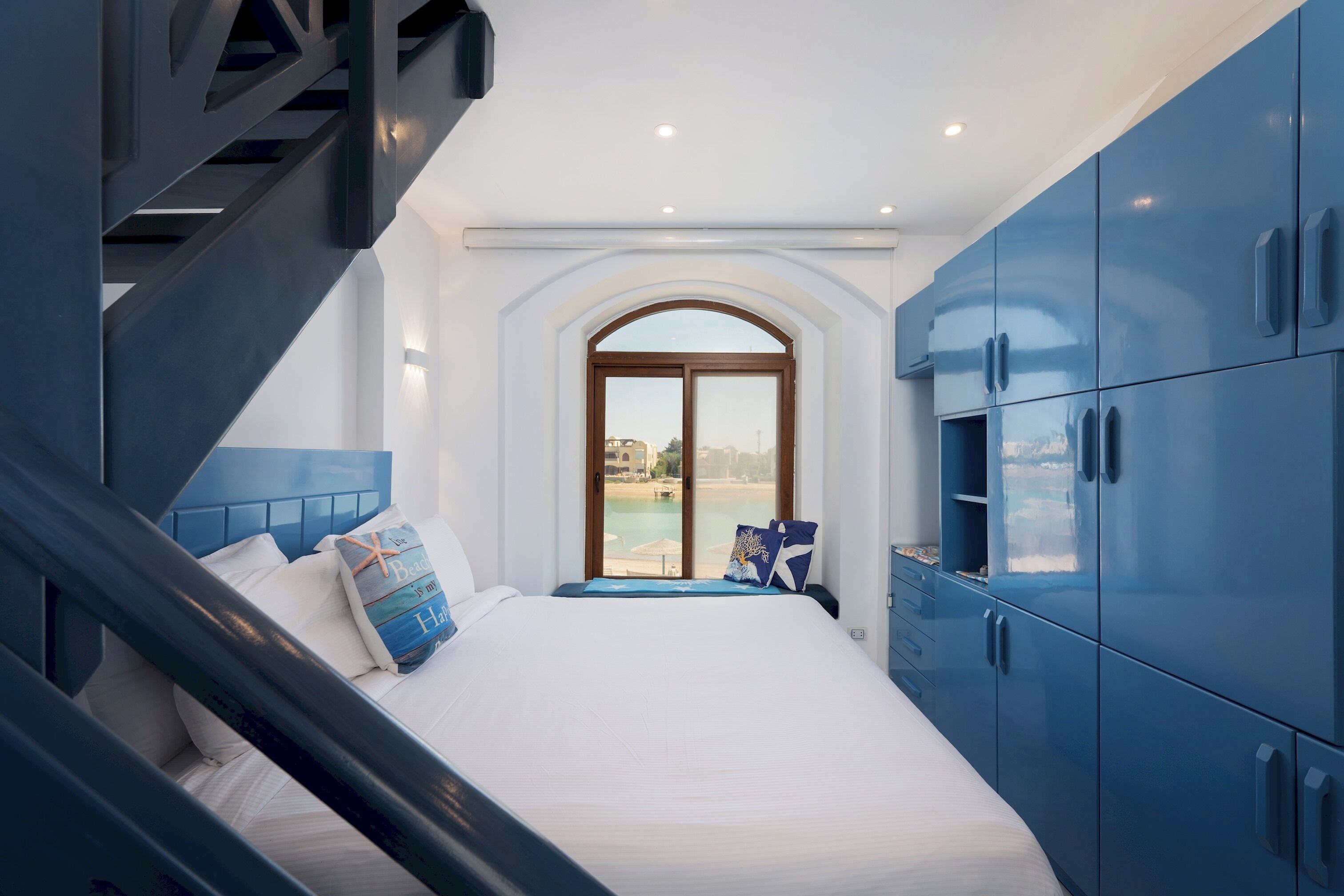 Une chambre à coucher avec un lit, une fenêtre et des armoires bleues.