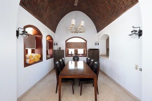 Un comedor con una larga mesa de madera, varias sillas y techo de ladrillo.