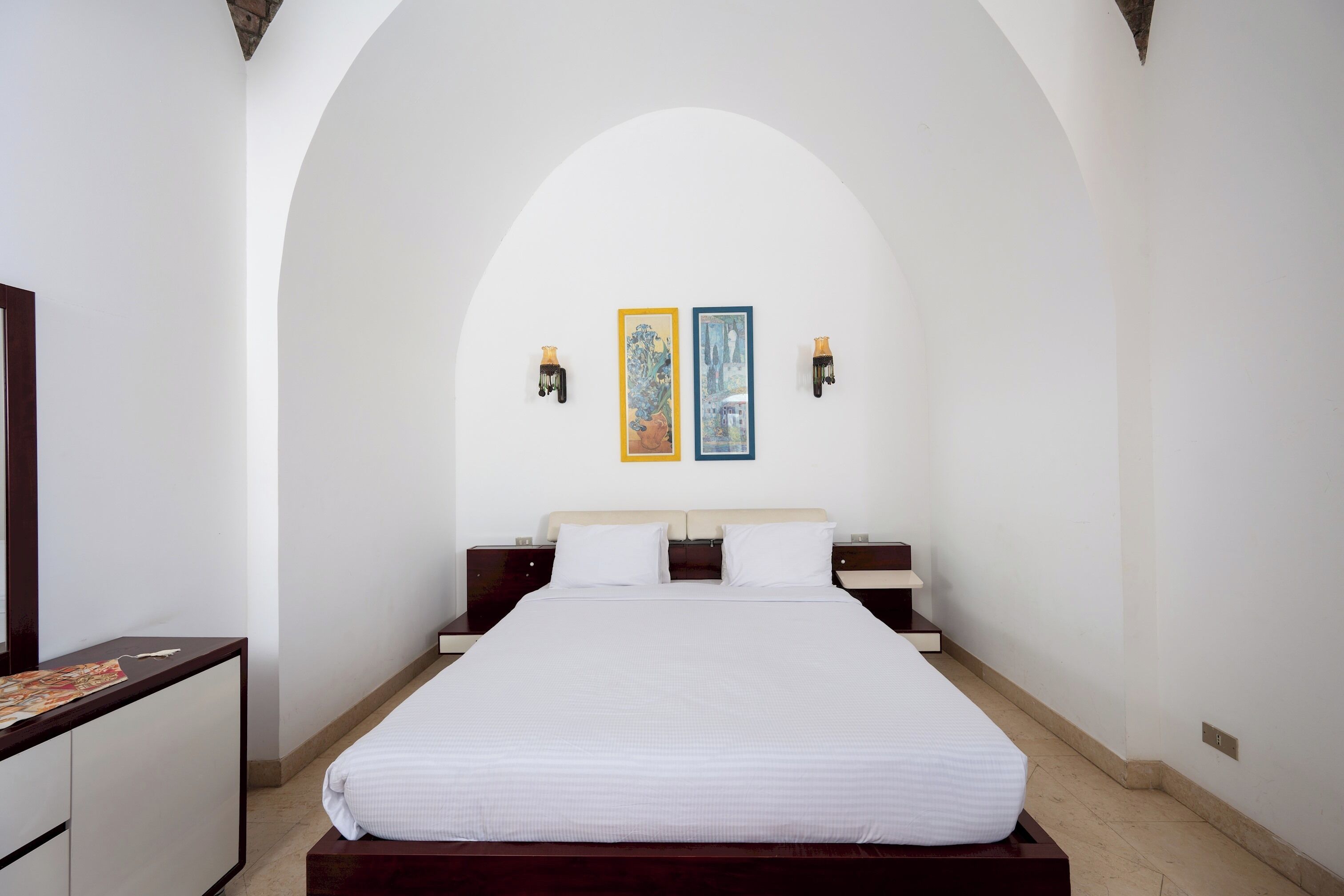 Een hotelkamer met een groot bed, een dressoir en twee wandlampen.