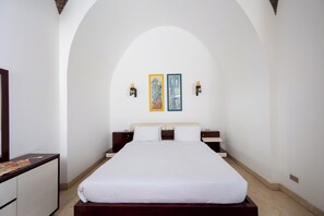 Habitación de hotel con una cama grande, un aparador y dos lámparas de pared.