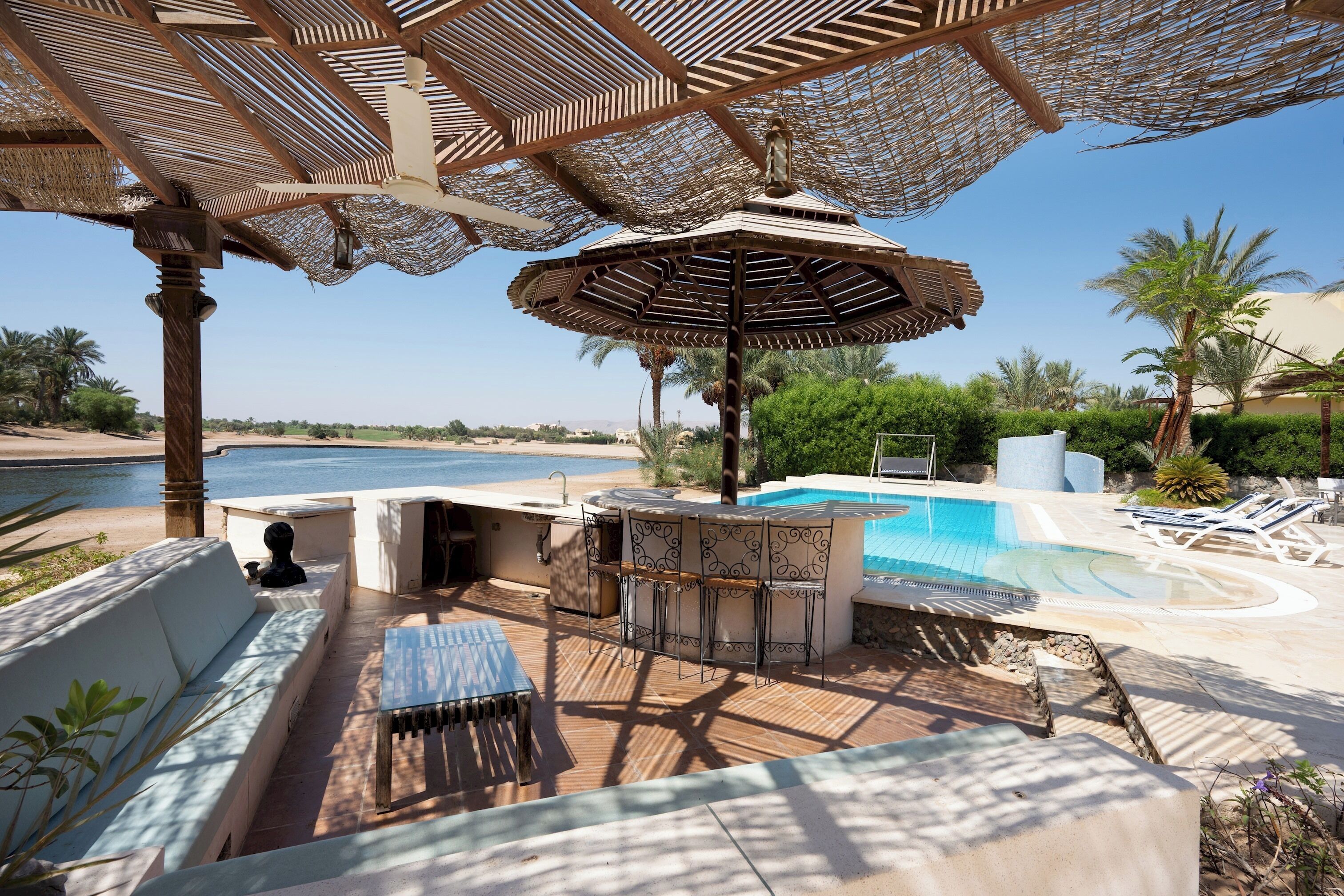 Un espace aménagé au bord de la piscine, avec un bar, des sièges et une vue sur la mer.