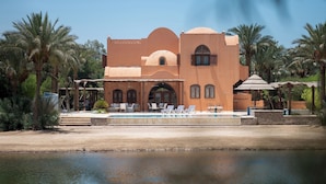 A building with a pool, palm trees, and a clear sky. - VESTA - Luxury Villa - 4BR - North Golf (II) (El Gouna)