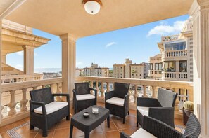 Ein Balkon mit Korbmöbeln, einem kleinen Tisch und Blick auf die Stadtlandschaft.