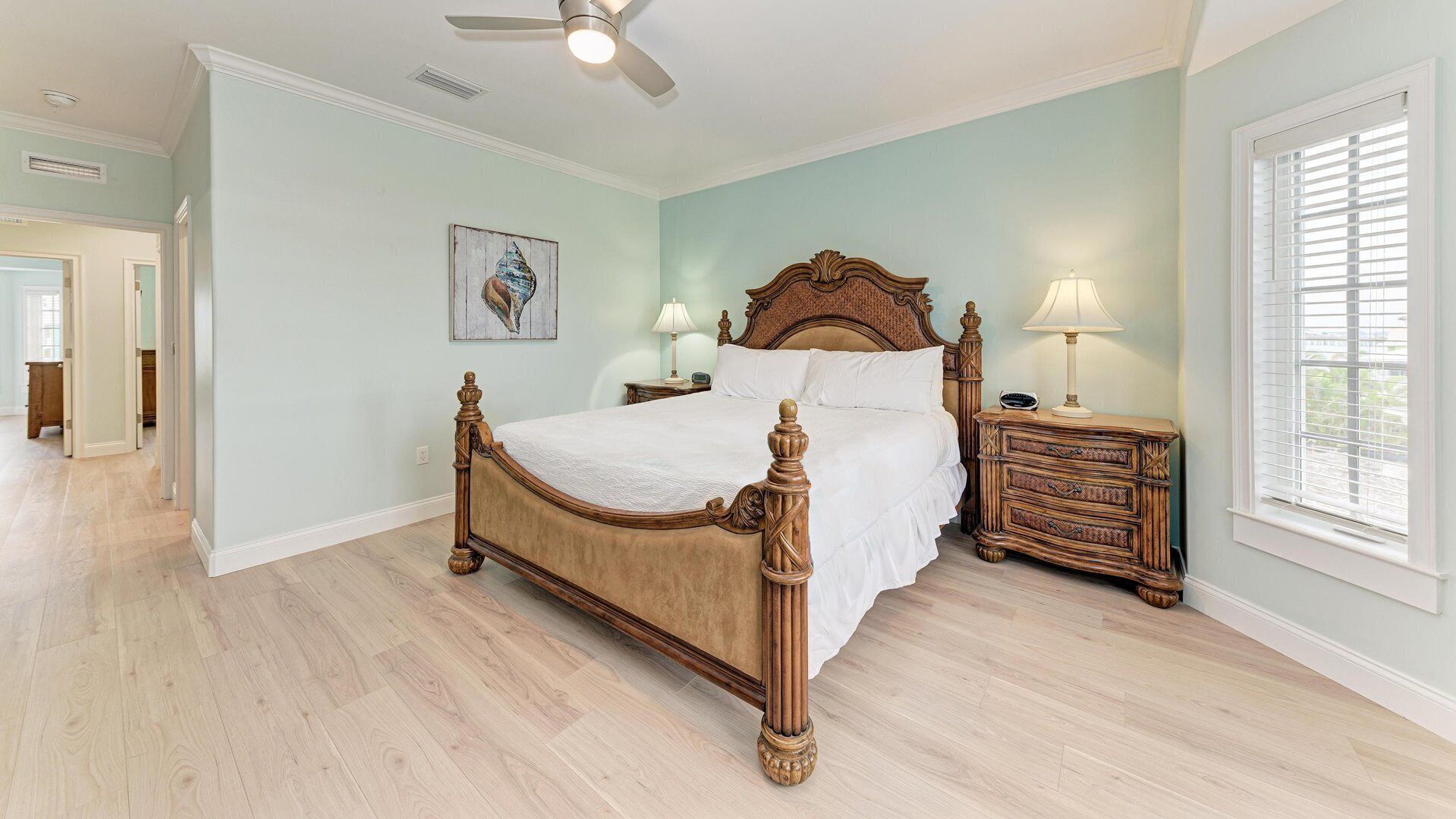 A bedroom with a wooden bed, a nightstand, a dresser, a ceiling fan, and a window with blinds.