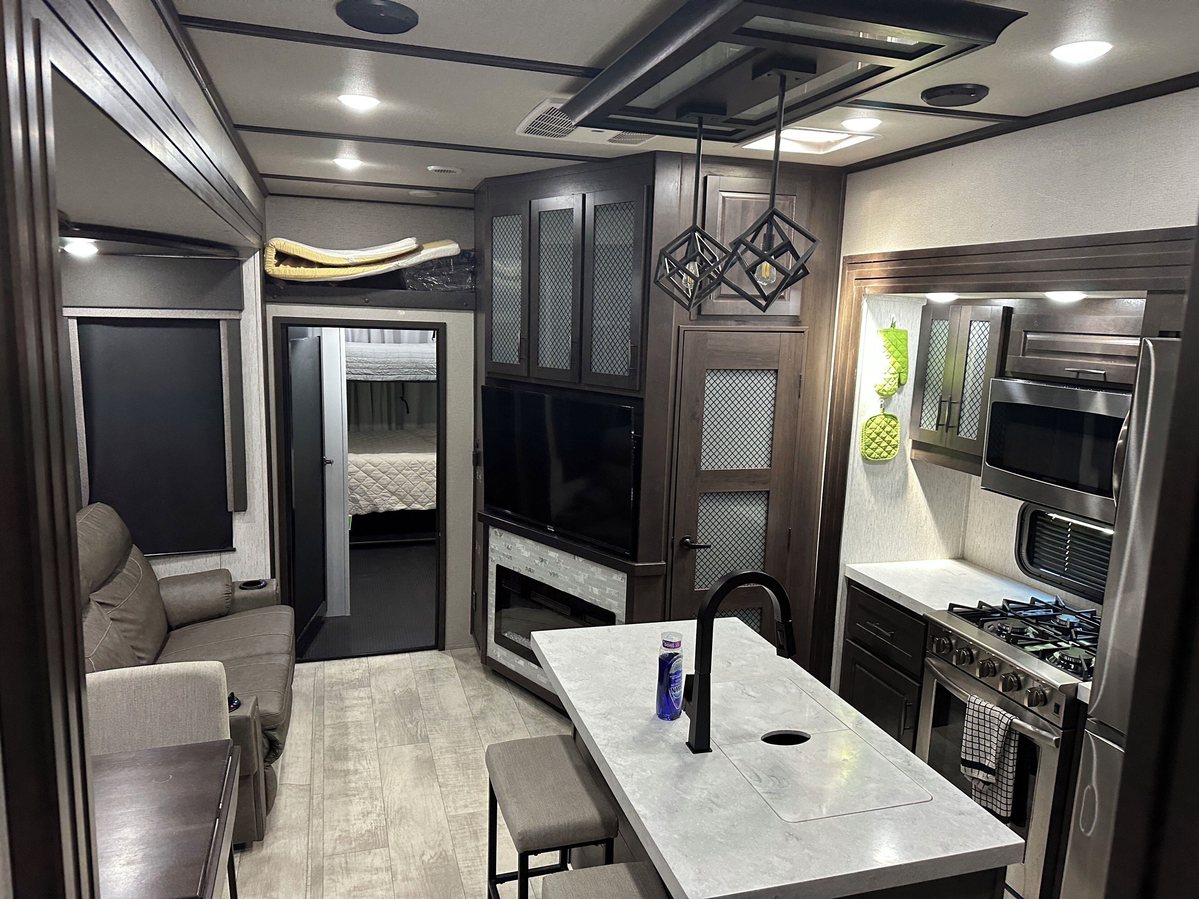 A compact kitchenette with a stove, oven, microwave, and a small dining area with a table and bench.