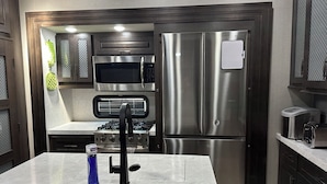 Eine moderne Küche mit Edelstahlgeräten, darunter Mikrowelle, Backofen und Kühlschrank.