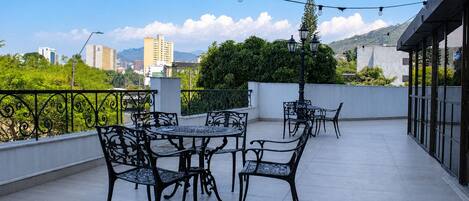 Una terraza en la azotea con mobiliario exterior y luces colgantes.