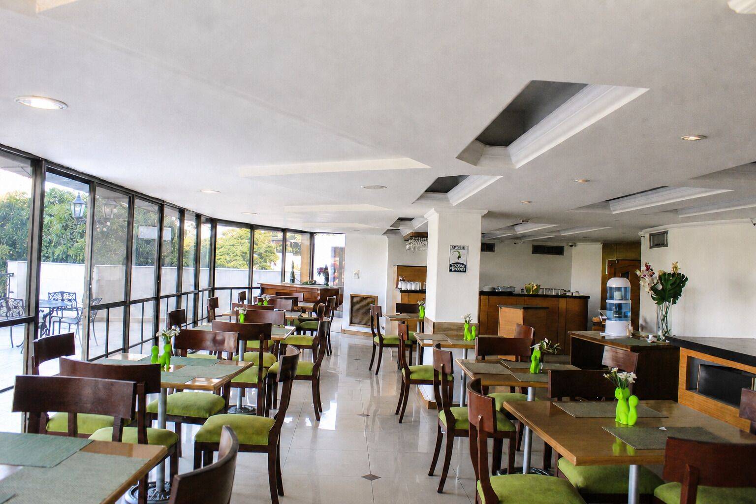 A restaurant with a curved layout, large windows, and a kitchen area visible in the background.