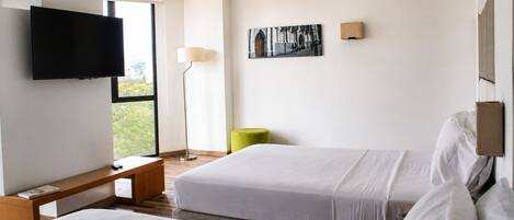 Une chambre d’hôtel avec deux lits, une télévision, un bureau, une chaise et un tableau au mur.