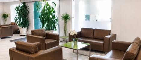 A modern lobby with leather sofas, a glass coffee table, and large windows.