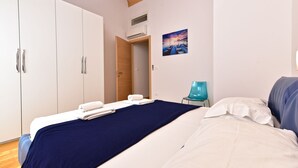 Ein Schlafzimmer mit einem Bett, einem Kleiderschrank, einem Sessel und einem Bild an der Wand.