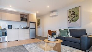 A modern apartment with a kitchen, a grey sofa, a coffee table, and artwork on the walls.