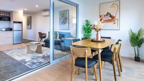A modern living space with a dining area, kitchen, and sliding glass doors leading to a balcony.