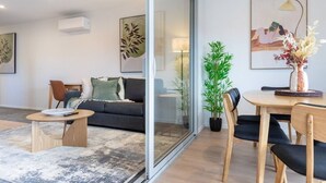 A modern living room with a sofa, coffee table, and dining area.