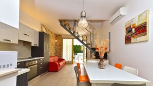 Una cocina moderna con comedor, escalera y mesa con sillas.