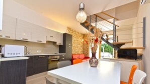 Una cocina moderna con comedor, horno empotrado y televisor.