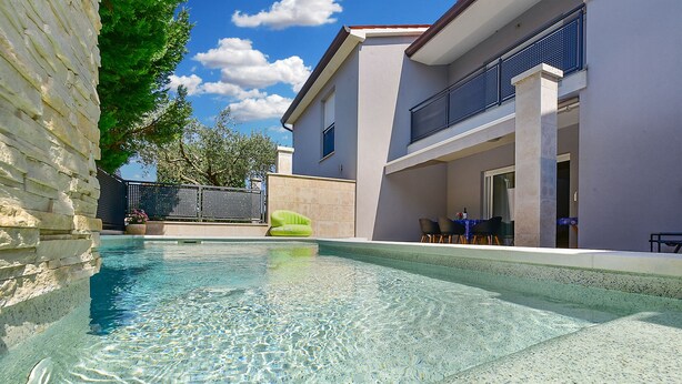 A swimming pool with clear water, a green lounge chair, and a building with a balcony. - House 2447/252732 (Istria - Banjole), 1000m from the beach (Banjole)