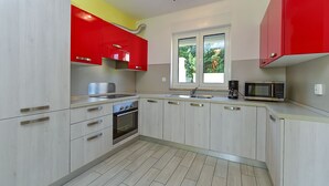 A modern kitchen with light wood cabinets, a stainless steel range, and a red accent wall. - House 2447/252732 (Istria - Banjole), 1000m from the beach (Banjole)