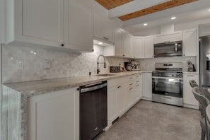A modern kitchen with white cabinets, a stainless steel dishwasher, a built-in oven, and a microwave. - Mountain Retreat, Theater Room, Hot Tub, Pac-Man Arcade & Stone Fireplace: Sugar Pine Lodge (South Lake Tahoe)