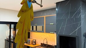 Eine moderne Küche mit schwarzem Marmor als Rückwand, einem eingebauten Backofen und einer hängenden Skulptur eines Papageis.