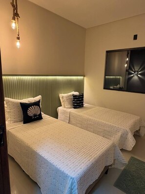 A hotel room with two beds, a green headboard, a wall-mounted mirror, and a light fixture. - Casa Brisa Baiana, leisure area, 250 meters from the beach. (Prado)