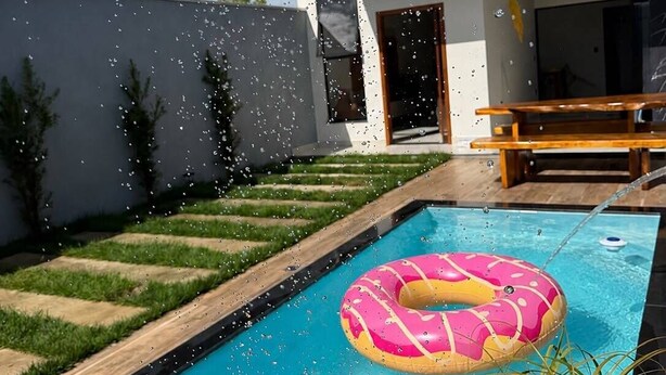 Ein modernes Haus mit Swimmingpool, einer Holzterrasse und einem rosa Schwimmreifen.