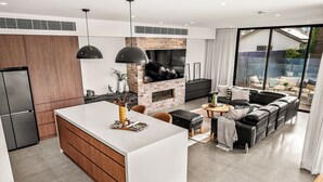 Eine moderne Küche mit einer zentralen Kochinsel, einem eingebauten Kamin aus Ziegeln und einem Essbereich mit einer schwarzen Ledersofa.